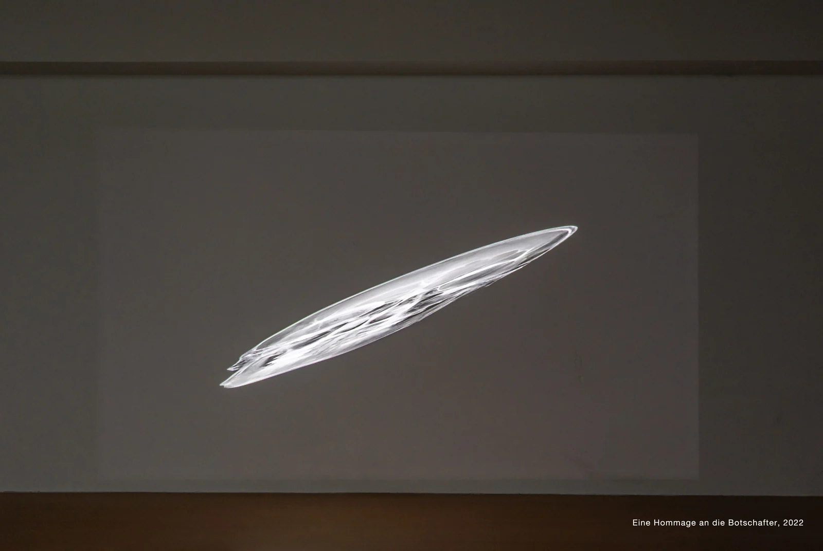 An elongated skull is projected diagonally across a bare wall.