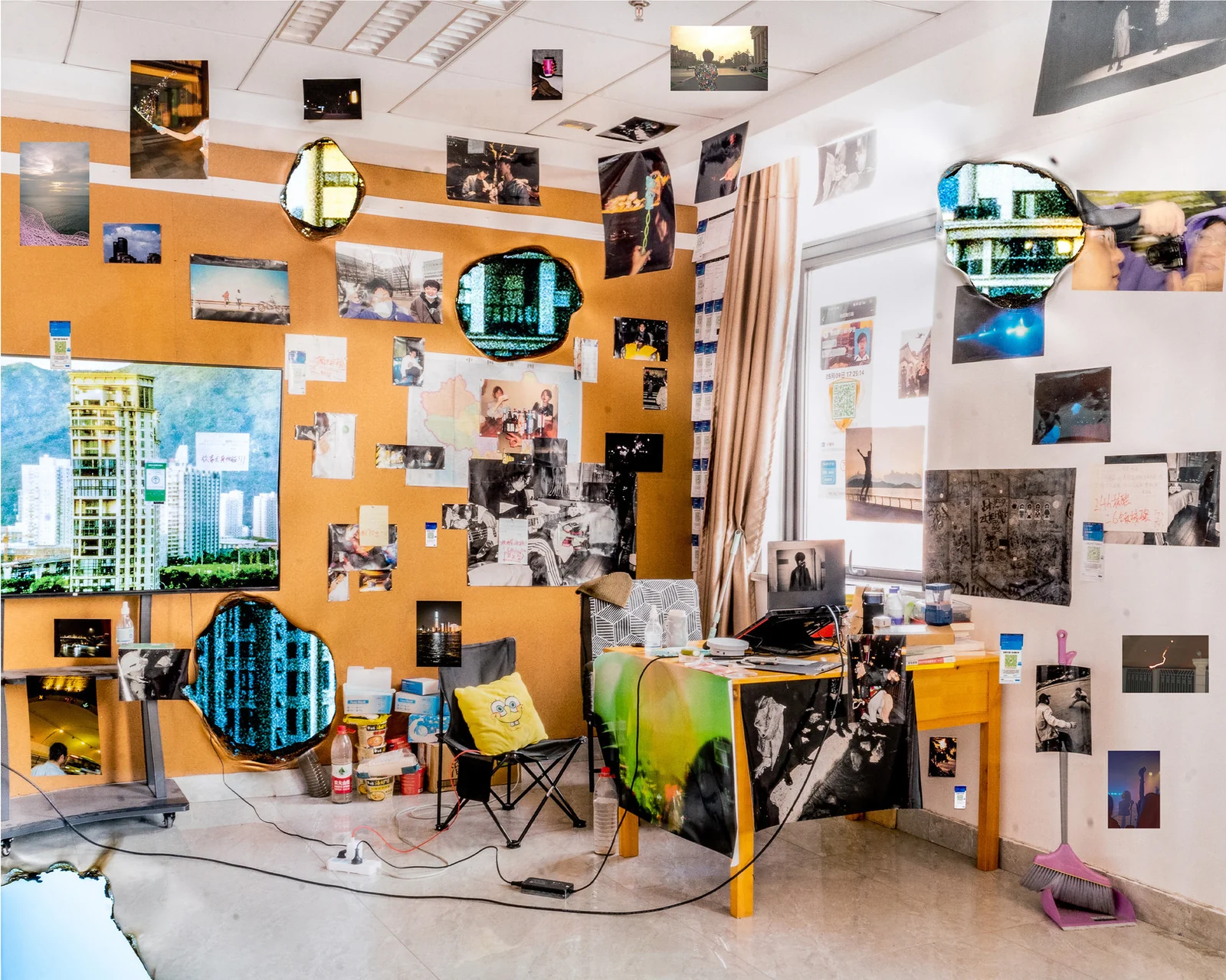 A studio filled with layered photographs, everyday objects and openings containing television imagery.