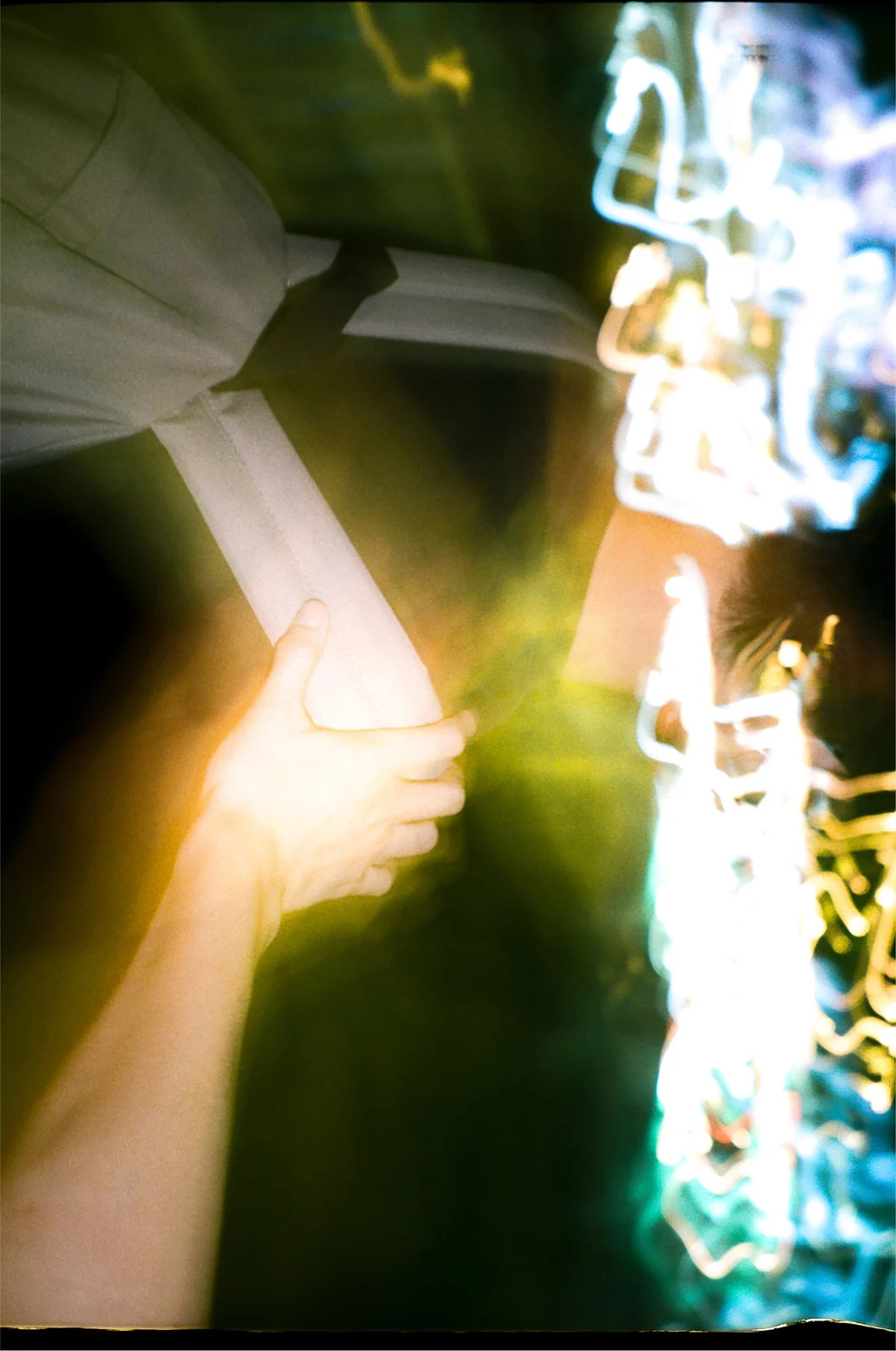 An arm and bright reflections in an abstract nighttime image.