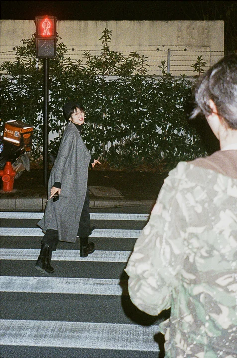 Two people pass each other at a pedestrian crossing at night.