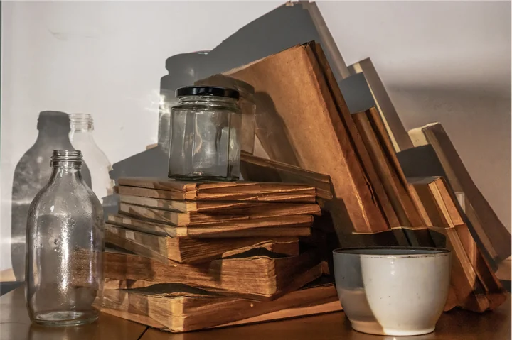 Pale ceramics, worn books and their projected silhouettes.
