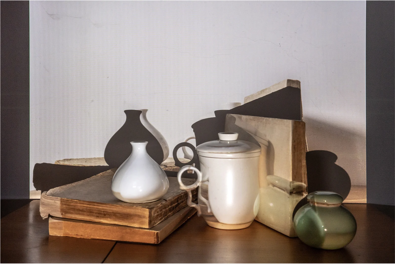 Dark vessels and books form a layered still life.
