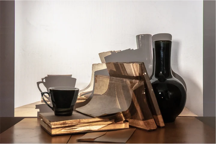 Glass jars and stacked books intersect with light and shadow.