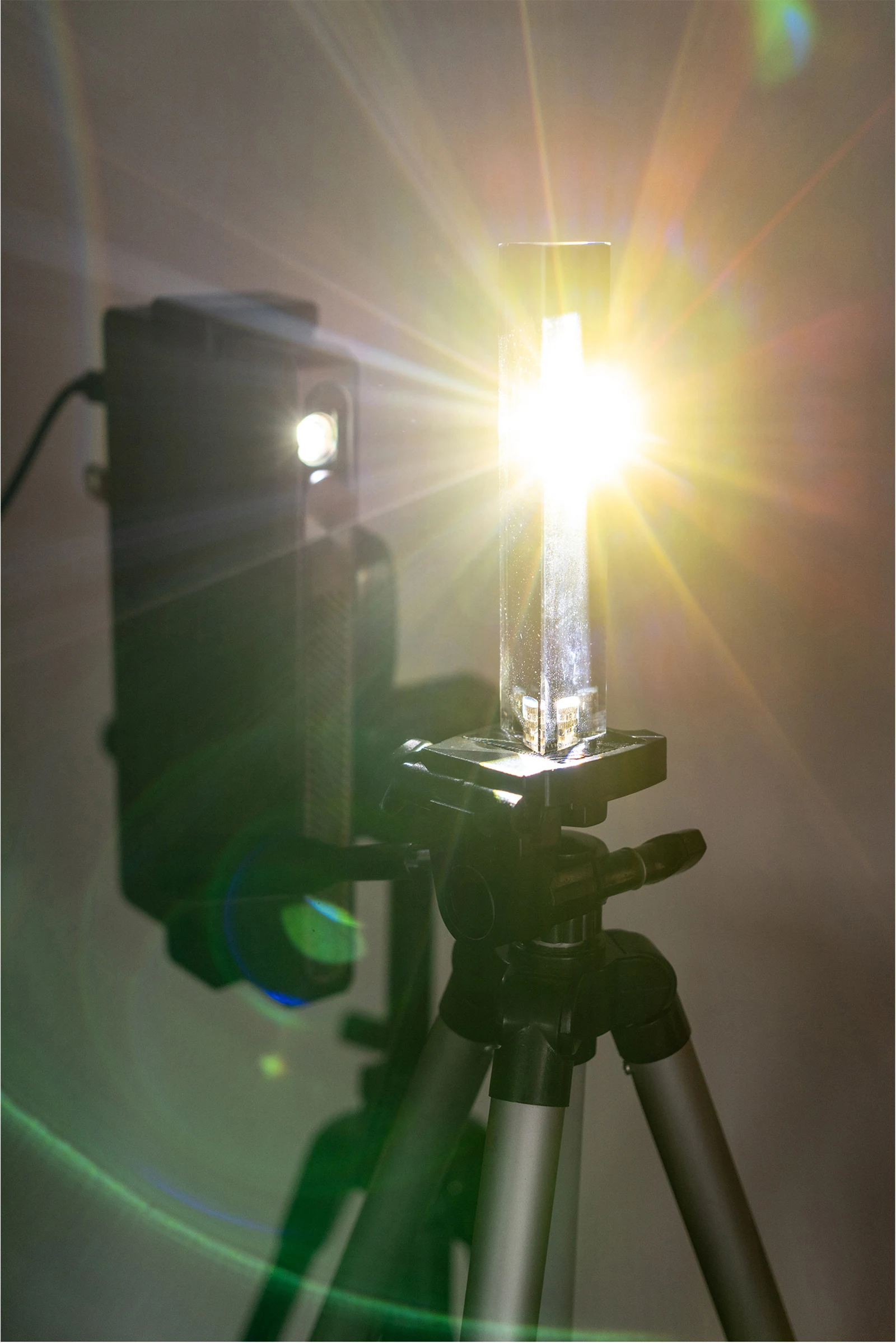 Bright projected light passes through a prism in front of a projector.