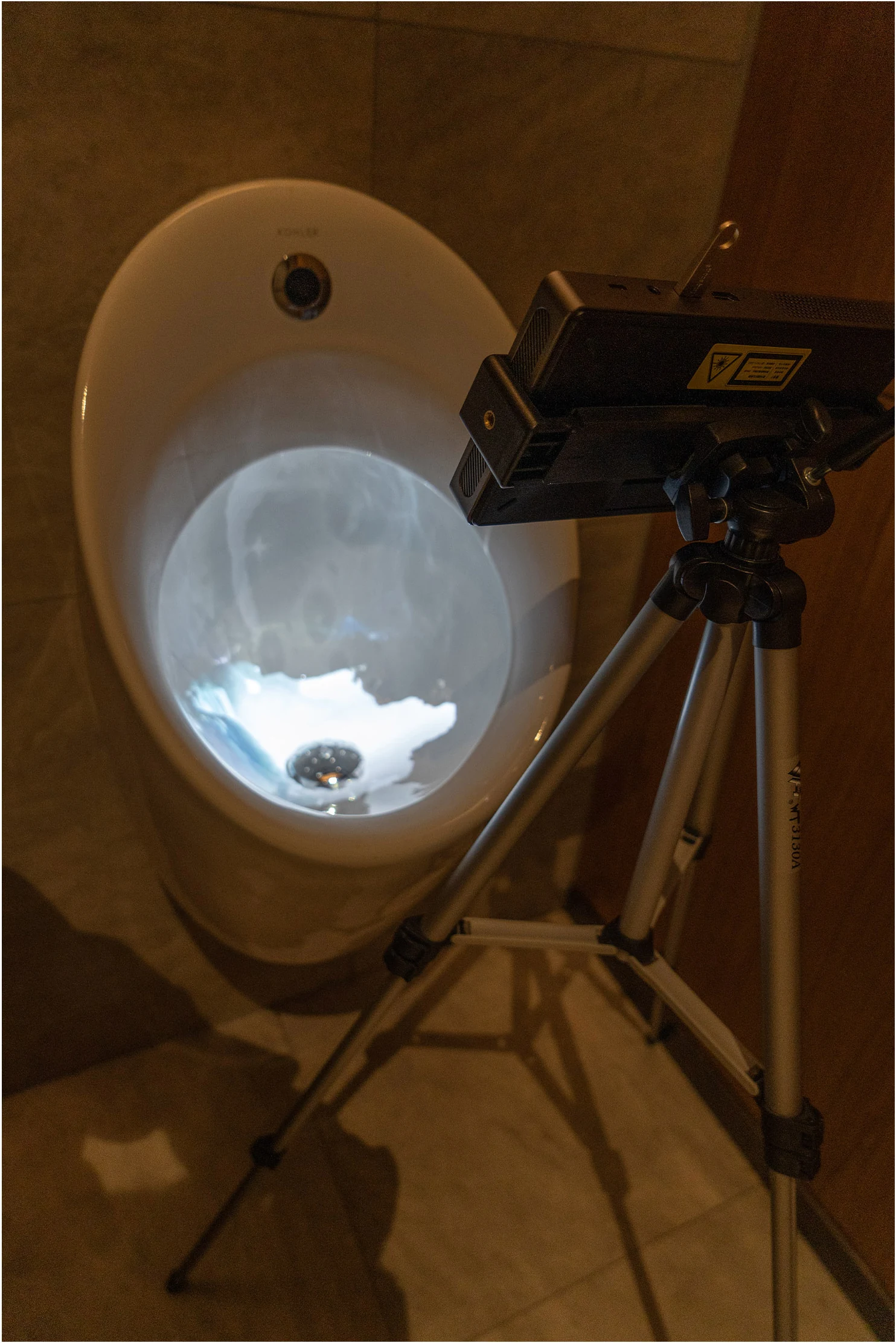 A projector on a tripod points into the ceramic basin.